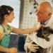 senior male veterinarian holding cat that little girl is petting